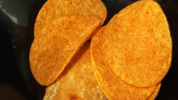 Knusprige Chips liegen auf einem schwarzen Teller, bereit zum Genie&szlig;en, frisch aus dem Gefrierfach.