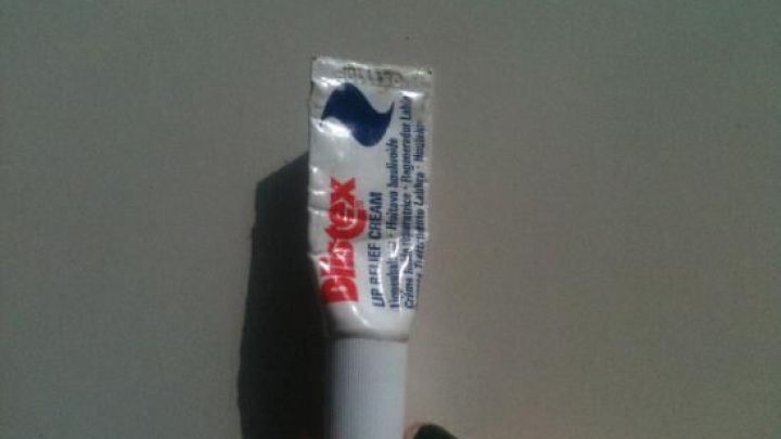 Ein Blistex-Tuben wird gehalten, um Pickel zu behandeln, auf einer neutralen Oberfl&auml;che ohne weitere Elemente im Hintergrund.