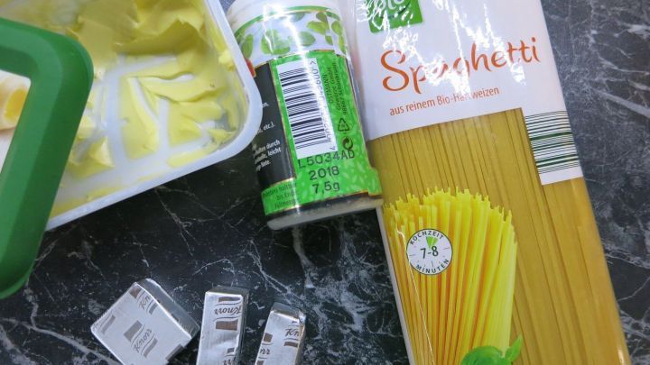 Ein Beh&auml;lter mit Butter und eine Packung Spaghetti liegen auf einer Arbeitsfl&auml;che, bereit zum Zubereiten von Rosmarin Butter mit Nudeln.
