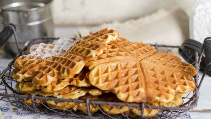 Eine &uuml;ppige Ansammlung von Quarkwaffeln liegt in einem Korb, umgeben von einer rustikalen K&uuml;chendekoration.