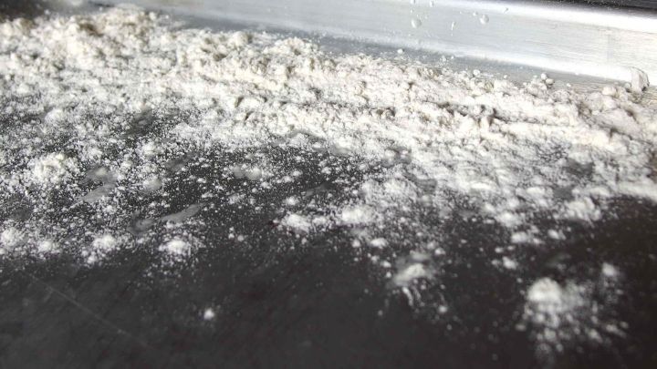 Mehl liegt verstreut auf einem Backblech, w&auml;hrend das Licht auf der Fl&auml;che gl&auml;nzt und die Vorbereitung zum Backen zeigt.