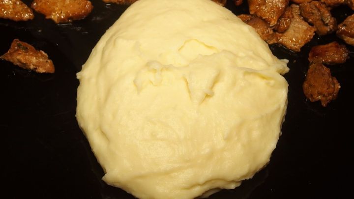 Ein cremiger Haufen Kartoffelp&uuml;ree liegt in der Mitte, umgeben von knusprigen, gebratenen Kartoffelst&uuml;ckchen.