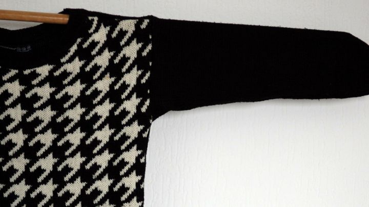 Ein gestreifter Wollpulli h&auml;ngt an einem Kleiderb&uuml;gel, bereit zum Trocknen in einem hellen Raum.