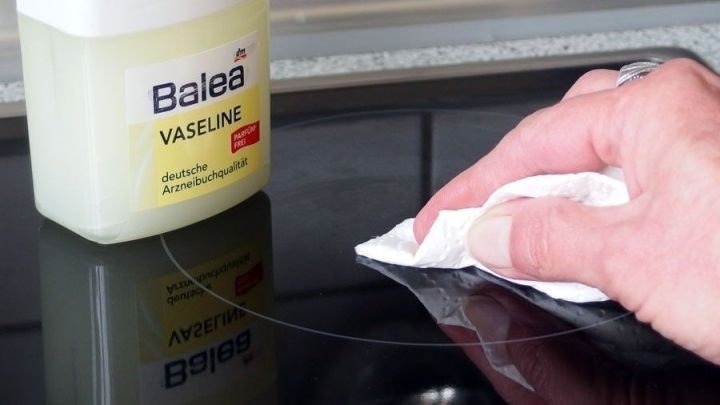 Ein Handtuch reinigt ein Glaskeramikfeld, w&auml;hrend eine Dose Vaseline daneben steht, um den Schutz zu unterst&uuml;tzen.