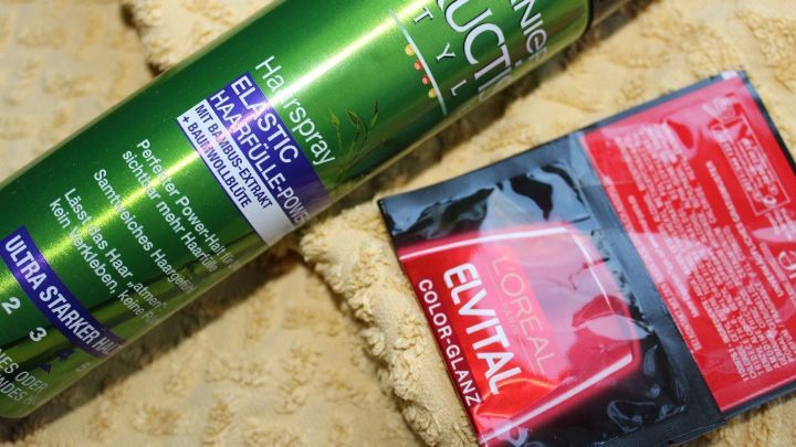 Ein Haarf&auml;rbemittel und eine Haarkur liegen auf einem weichen, hellen Handtuch, das f&uuml;r die Anwendung vorbereitet ist.