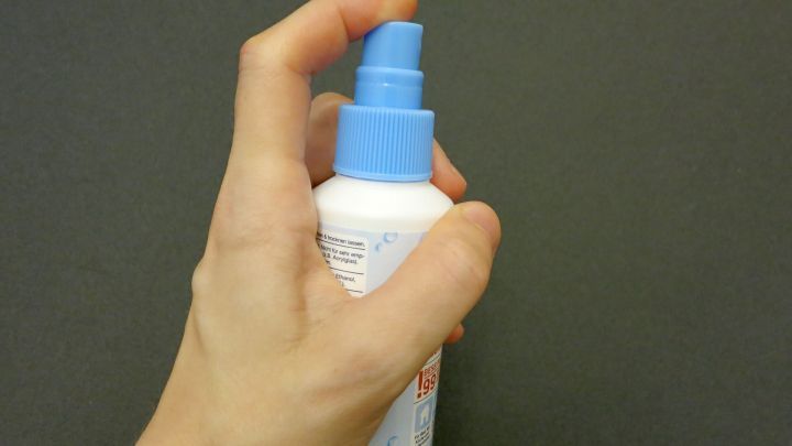 Eine Hand h&auml;lt eine Spr&uuml;hflasche, die anscheinend zum Schutz vor Pickeln nach der Intimrasur verwendet wird.