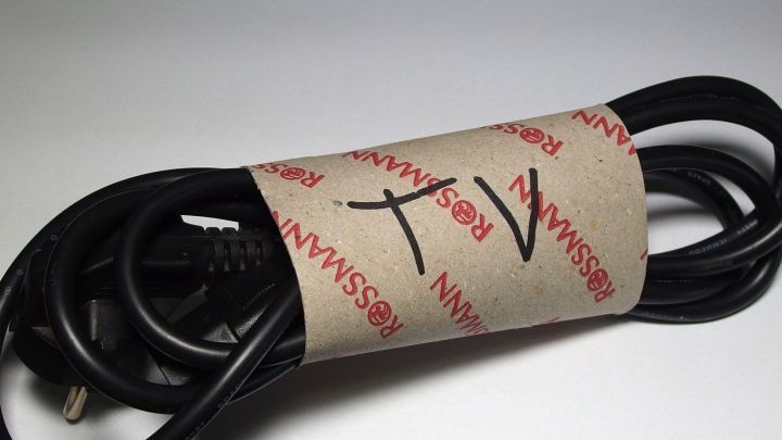 Ein Kabel ist aufgerollt und mit einem Etikett beschriftet, das "TV" zeigt, um Ordnung im Kabelsalat zu schaffen.