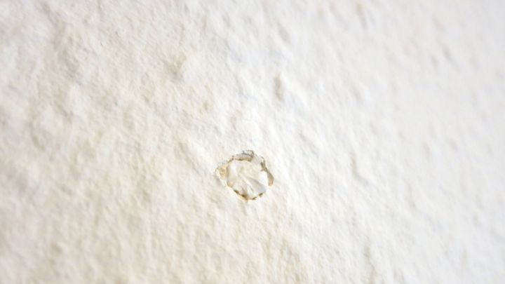 Ein Nagel steckt in einer wei&szlig;en Wand, um Papiertaschent&uuml;cher zu befestigen, in einem minimalistischen Raum ohne weitere Dekoration.