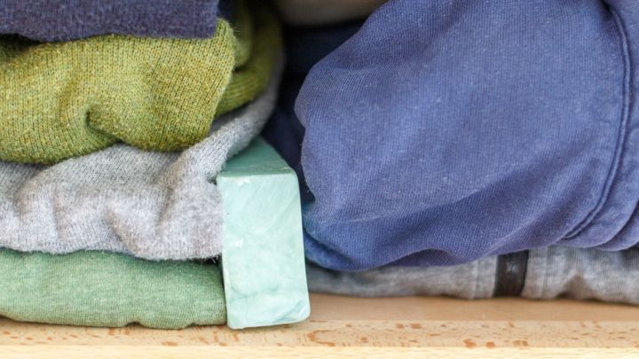 Falten von bunten Kleidungsst&uuml;cken liegen ordentlich gestapelt in einem Holzregal und schaffen so ein prima Klima im Kleiderschrank.