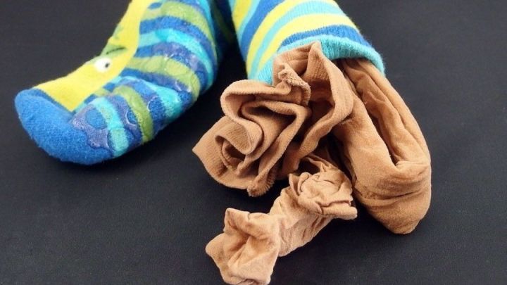 Feinstrumpfhosen liegen in bunten Socken auf einem dunklen Untergrund, bereit zum Waschen in der Maschine.