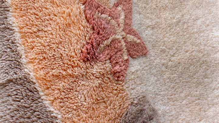 Ein Teppich zeigt eine farbige Fl&auml;che mit einem auff&auml;lligen Muster, w&auml;hrend Druckerschw&auml;rze darauf verteilt ist.