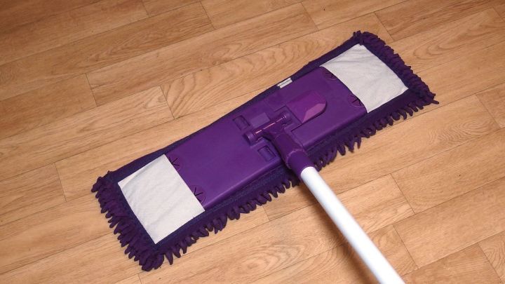 Ein Reinigungstuch in lila liegt auf gl&auml;nzendem Laminatboden, bereit zum Wischen mit Essigessenz f&uuml;r den strahlenden Effekt.