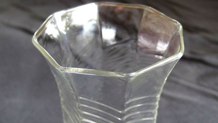 Eine klare Glasvase steht auf einem dunklen Untergrund, bereit, abgekochtes Blumenwasser zu empfangen.