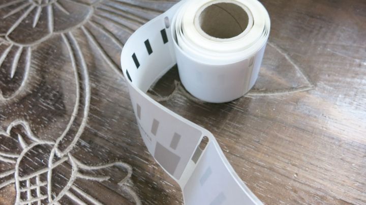 Ein Aufkleberrollenobjekt liegt auf einem h&ouml;lzernen Tisch, bereit zum Adressieren f&uuml;r den Urlaub.