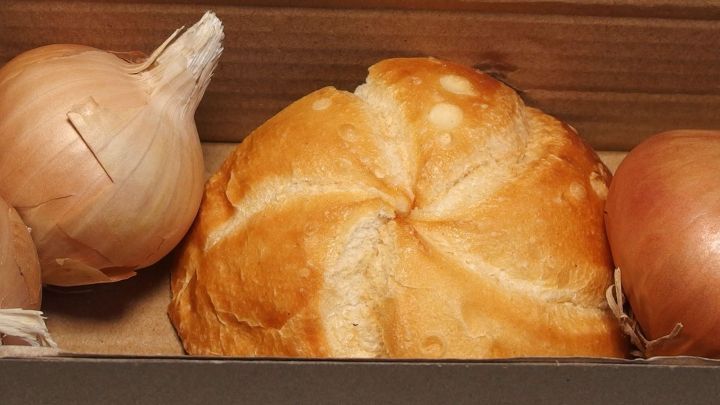 Zwiebeln liegen neben einem Br&ouml;tchen in einem Karton, wobei die Zwiebeln nicht keimen.
