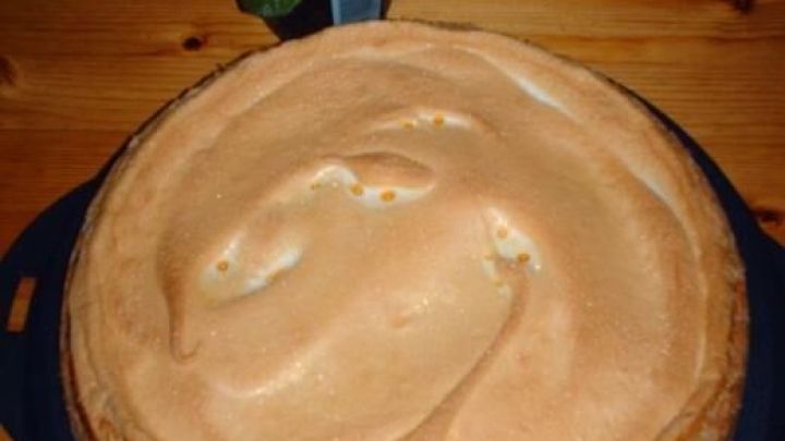 Ein Engelstr&ouml;pfchenkuchen liegt auf einem schwarzen Teller, umgeben von einem bl&uuml;henden Topf mit gelben Blumen auf einem Holztisch.