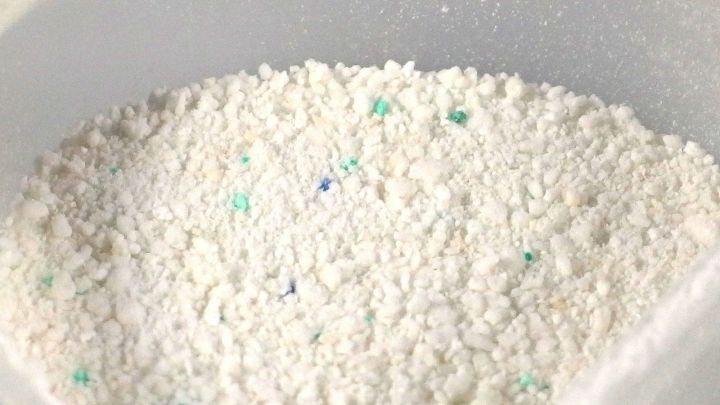 Wei&szlig;es Waschpulver in einer transparenten Sch&uuml;ssel, bereit zur Anwendung im Putzmittelprozess zum Reinigen von Kleidung.