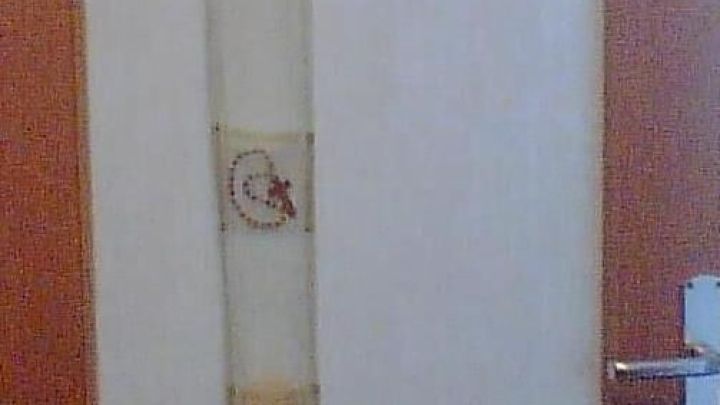 Eine Glast&uuml;r ist teilweise mit einem vertikalen Stoffband mit bunten Mustern verziert, umgeben von einem h&ouml;lzernen T&uuml;rrahmen.