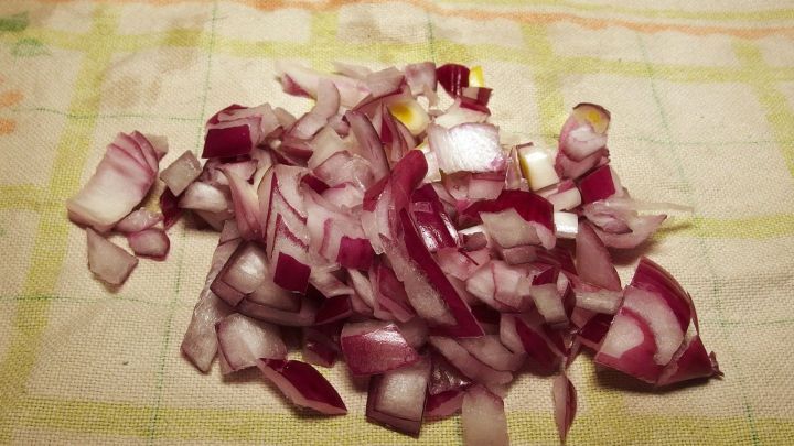 Geschnittene rote Zwiebeln liegen auf einem K&uuml;chentuch, bereit f&uuml;r die Anwendung in einem Zwiebelwickel gegen Mandelentz&uuml;ndung.