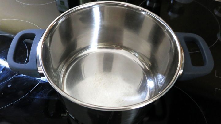 Ein leerer, gl&auml;nzender Kochtopf steht auf dem Kochfeld und wartet darauf, angebranntes &Ouml;l zu entfernen.