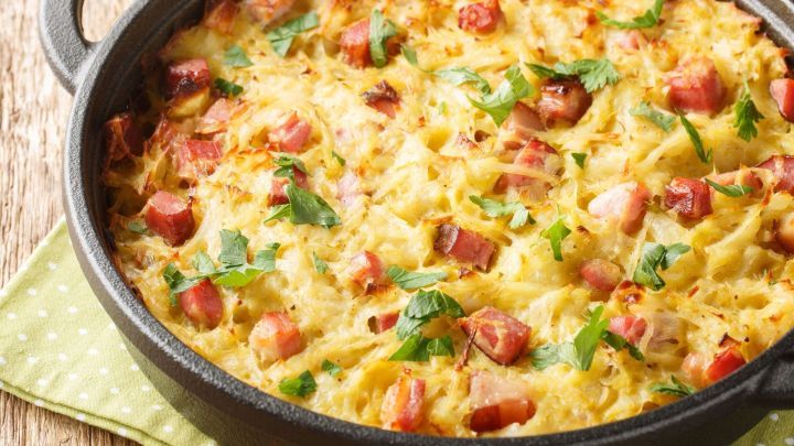 Ein dampfender J&auml;gertopf mit knusprigem Belag aus Kartoffeln und Schinken, serviert in einem schwarzen Gusseisentopf.