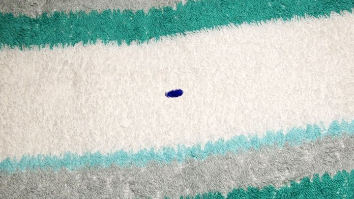 Auf einem gestreiften Handtuch liegt ein kleiner blauer Kugelschreiberfleck, der die Oberfl&auml;che verschmutzt.