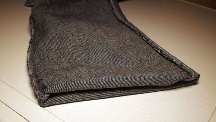 Helle Jeans liegen gefaltet auf einer Waschmaschine, bereit f&uuml;r die W&auml;sche, um ihre Lebensdauer zu verl&auml;ngern.