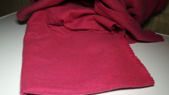 Ein rotes Fleece liegt auf einem Tisch, bereit zum Waschen, um seine Farbe und Weichheit zu erhalten.