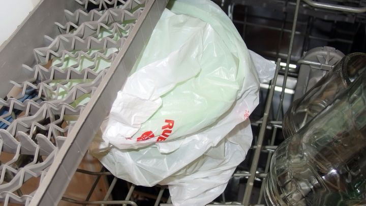 Eine Plastikt&uuml;te mit gefrorenem Inhalt liegt im Geschirrsp&uuml;ler und taut auf, um das Geschirr zu reinigen.