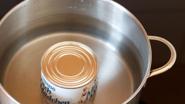Eine Dose mit Milchcondensat schwimmt in einem Topf mit Wasser, um Dulce de leche durch Erhitzen zu erzeugen.