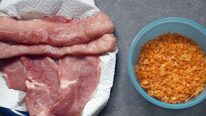 Saftige Fleischst&uuml;cke liegen auf einem K&uuml;chentuch, w&auml;hrend altes Knabbergeb&auml;ck in einer Sch&uuml;ssel bereitsteht.