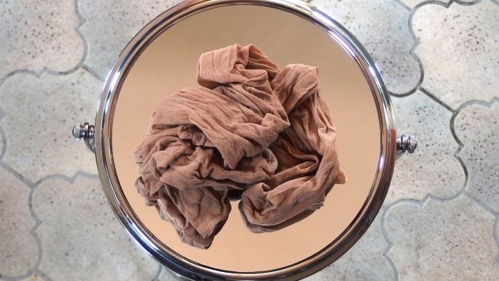 Ein streifenfreier Spiegel zeigt einen zerknitterten Stoff in der Mitte, auf einem dekorativen Untergrund liegend.