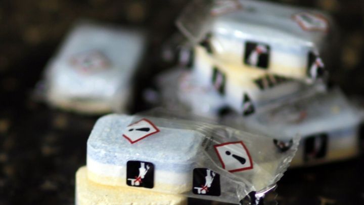 Ein Sp&uuml;lmaschinentab liegt auf einer dunklen Oberfl&auml;che, bereit zur Verwendung, um einen verkrusteten Gasherd zu reinigen.