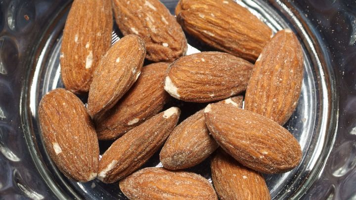 Mandeln liegen in einer Glassch&uuml;ssel und warten darauf, gesch&auml;lt und enth&auml;utet zu werden, ideal f&uuml;r die Weihnachtsb&auml;ckerei.