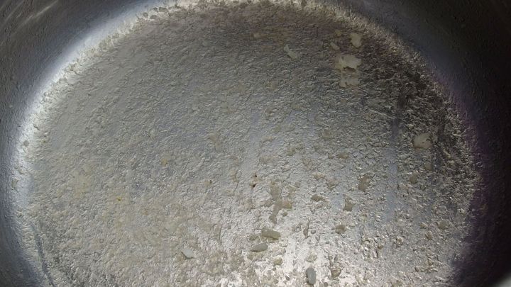 Ein eingebrannter Topf liegt auf einer Arbeitsfl&auml;che, mit sichtbaren, verh&auml;rteten R&uuml;ckst&auml;nden im Inneren.