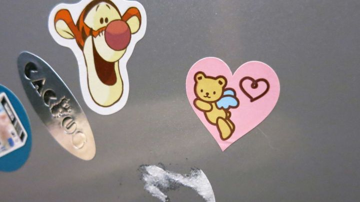 Auf einer grauen K&uuml;chenschrankoberfl&auml;che befinden sich Aufkleber, w&auml;hrend die Reste von Margarine sichtbar sind.