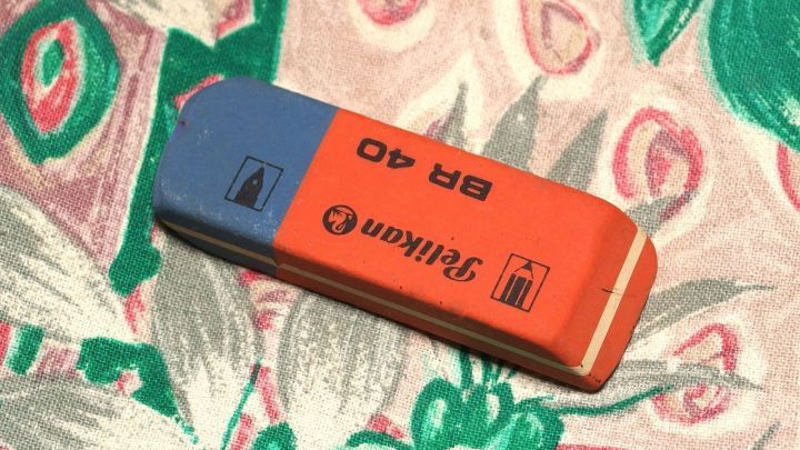 Ein Radiergummi liegt auf einem bunten Stoff mit floralem Muster, bereit, um Kaugummi zu entfernen.