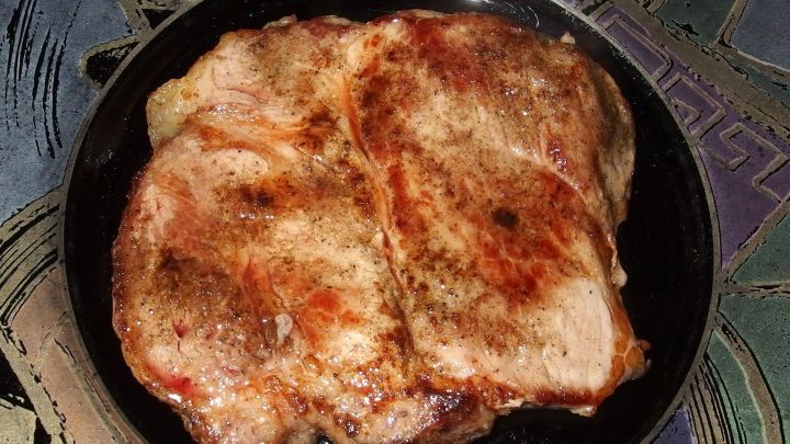 Zarte, gegrillte Fleischst&uuml;cke liegen auf einem schwarzen Teller in einer bunten Umgebung. Essig wird verwendet, um die Textur zu verbessern.