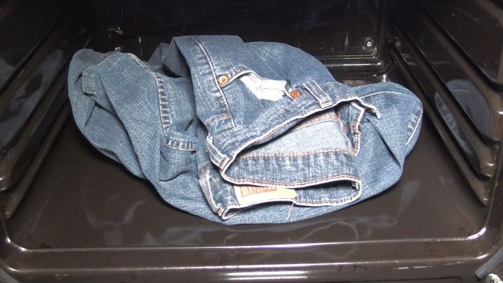 Eine zerknitterte Jeans liegt im Backofen, w&auml;hrend dieser m&ouml;glicherweise zum schnellen Trocknen genutzt wird.