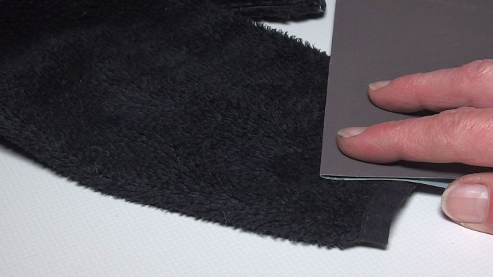 Ein Handwerker verwendet Sandpapier, um gl&auml;nzende Stoffe zu bearbeiten, um die Oberfl&auml;che zu gl&auml;tten.