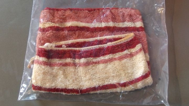 Ein einget&uuml;teter Waschlappen liegt in einer durchsichtigen Plastikverpackung auf einem Tisch, bereit zur Verwendung.