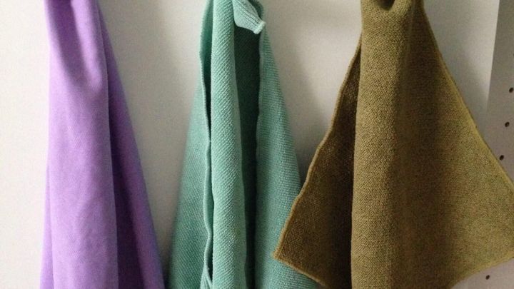 T&uuml;cher h&auml;ngen an Saugn&auml;pfen auf einer wei&szlig;en Schrankt&uuml;r; von links nach rechts: lila, gr&uuml;n, braun.