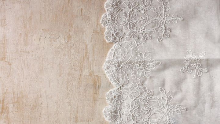 Ein sch&ouml;nes, wei&szlig;es Tuch mit zarter Spitze liegt auf einer hellen Unterlage, bereit zum St&auml;rken mit Speisest&auml;rke.