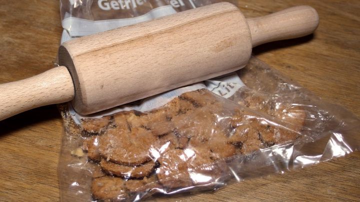 Kekse werden mit einem Nudelholz in einem Gefrierbeutel zerkr&uuml;melt, auf einer Holzoberfl&auml;che.