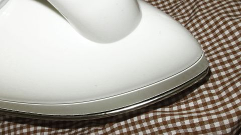 Das Dampfbügeleisen gleitet sanft über ein kariertes Hemd, um Falten schnell zu entfernen und es vorzubereiten.