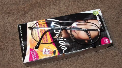 Eine Brille liegt auf einer Haarfärbemittel-Packung, die das Tönen von Haaren trotz Brille thematisiert.
