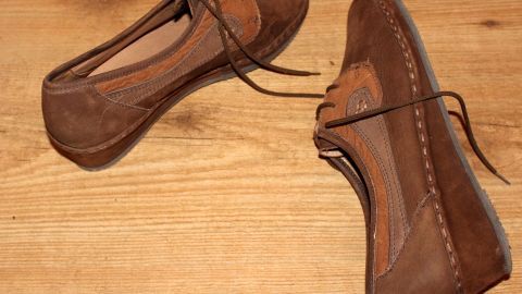 Stoff- und Wildlederschuhe liegen auf einem Holztisch, bereit zur Reinigung mit Polsterschaum.