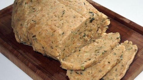 Leckere Semmelknödel liegen auf einem Holzbrett, einige in Scheiben geschnitten und bereit zum Servieren.