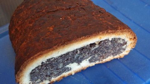 Ein Kuchenstück zeigt eine goldbraune Kruste, die einen dunklen, saftigen Kern verbirgt, der auf einem blauen Kuchenteller liegt.