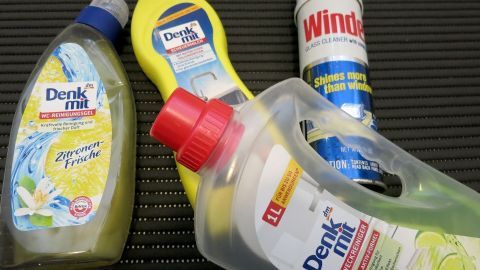 Unnötig teure Putzmittel kann man durch günstigeres Citrus-Spülmittel beim Putzen im Haushalt ersetzen. Verschiedene Flaschen mit Spezialputzmittel liegen auf einer Unterlage, bereit zum Reinigen von Oberflächen im Haushalt.